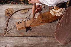Fire friction's technique of turning spindle through bow on wooden board. 